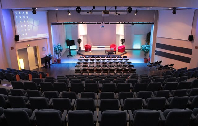 Amphithéâtre auditorium setup with red chairs for engaging presentations and discussions.
