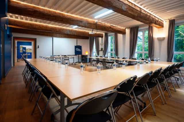 Modern meeting room with natural light, rustic beams, ideal for corporate events.