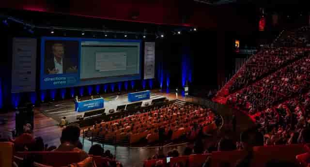 Lyon Convention Centre event with speaker on stage and audience in tiered seating.