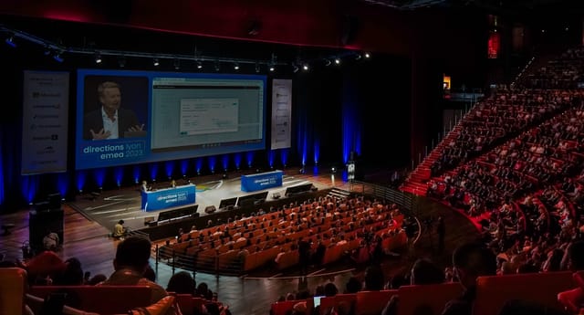 Lyon Convention Centre event with speaker on stage and audience in tiered seating.