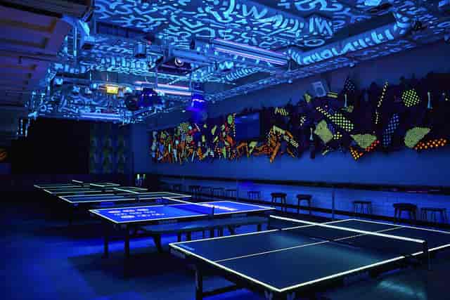 Communal project space with neon ping pong tables for networking and team building events.