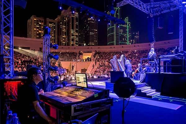 Outdoor conference in Al Majaz Amphitheatre with illuminated stage and city backdrop.