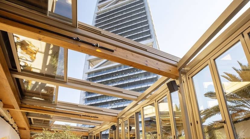 Modern restaurant with glass walls, ideal for corporate events overlooking skyscraper.
