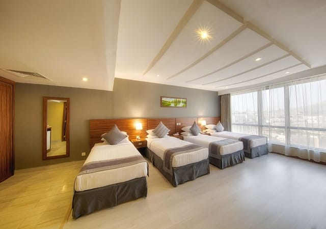Al Safwah Hotel suite with multiple beds, ideal for team retreats and conferences.