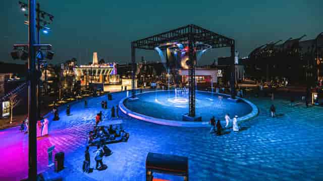 Vibrant outdoor event space with colorful lights and artistic water feature for receptions.