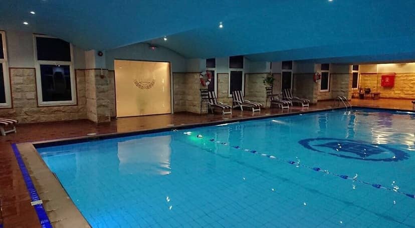 Outdoor swimming pool with tranquil blue lighting, ideal for wellness retreats and social events.