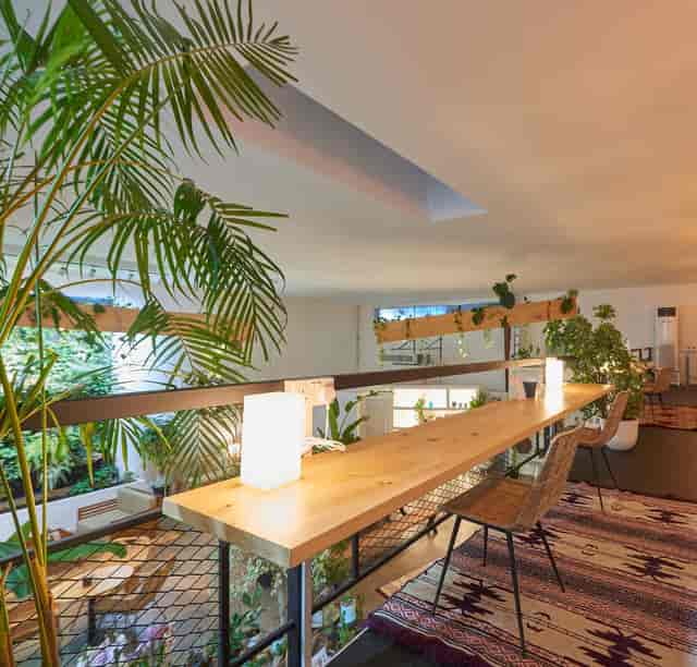 Outdoor garden event space with long wooden table and lush greenery for gatherings.