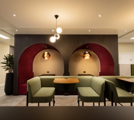 Modern office meeting space in Gilbanks, Manchester with green seating and warm lighting.