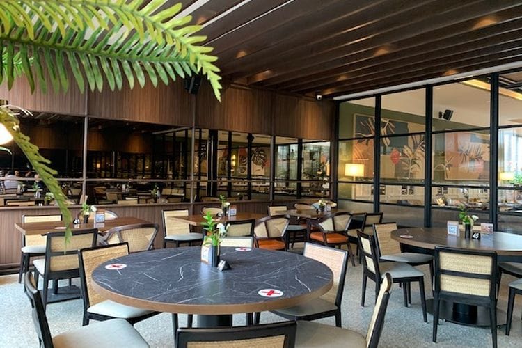 Versatile dining area with natural light and greenery for events in Penang Bistro.