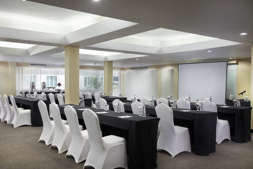 Ballroom at Grandkemang Hotel Jakarta with elegant black tables and white chairs, ideal for meetings.
