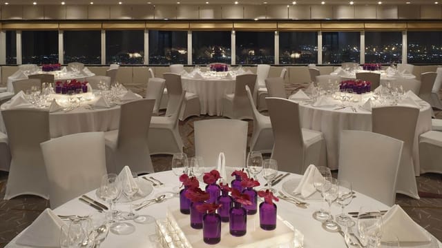 Gulf Auditorium in Dubai Opera, elegant dinner setup with purple centerpieces, corporate events.