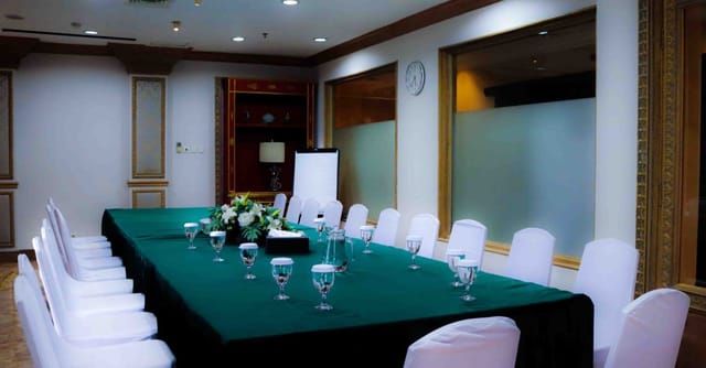 Corporate meeting room with green tablecloth, ideal for productive events.