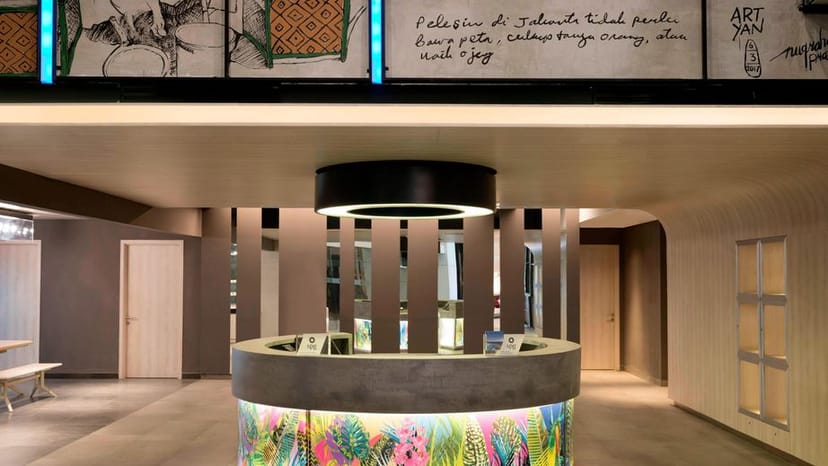 Modern reception area for meetings at Aloft Jakarta, featuring vibrant artwork and open layout.