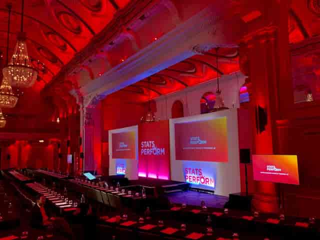 Corporate event setup in Grand Connaught Rooms with LED lighting and long-table configuration.