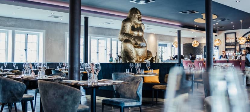 Modern dining room in Blue Mare Hamburg with golden gorilla sculpture, perfect for upscale events.