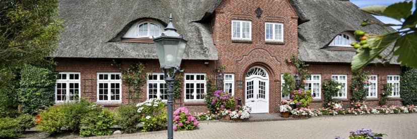 Thatched-roof restaurant venue for weddings and outdoor events, surrounded by vibrant landscaping.