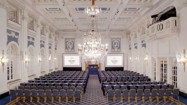 Goldener Saal in Hotel Atlantic Hamburg, elegant conference venue with chandelier and dual screens.
