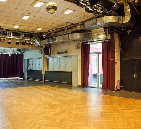 Versatile event space in Kulturhaus Eidelstedt with polished wooden flooring and elegant curtains.
