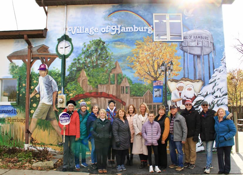 Community gathering at art gallery with vibrant mural in The Village, celebrating local culture.