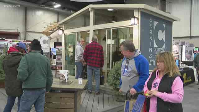Cottage-style booth at outdoor fair, bustling with attendees networking and exploring.