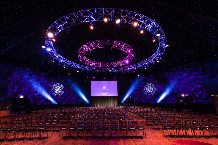 Glass Room Suites conference hall with circular lighting truss, ideal for events and presentations.