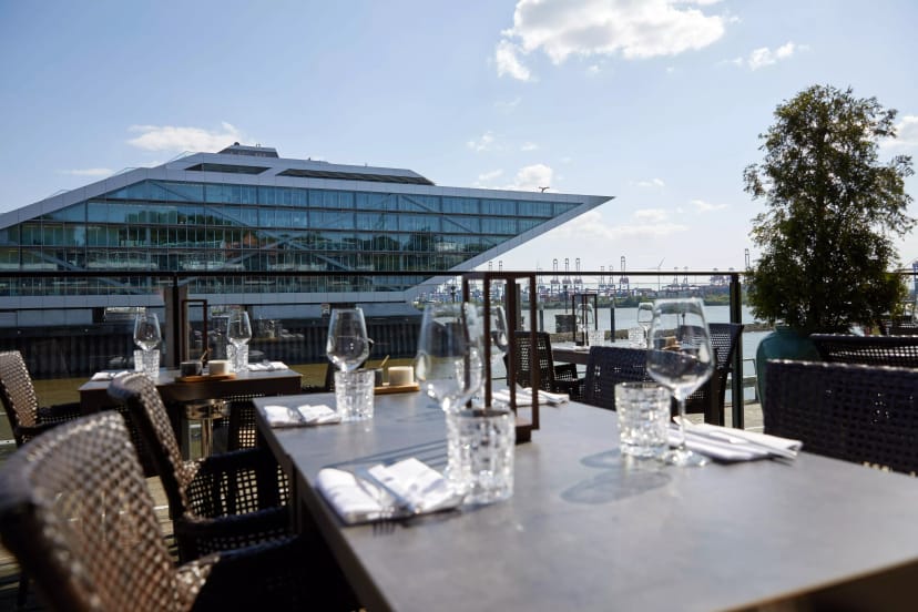 Elegant outdoor dining setup at modern waterfront restaurant for corporate events.