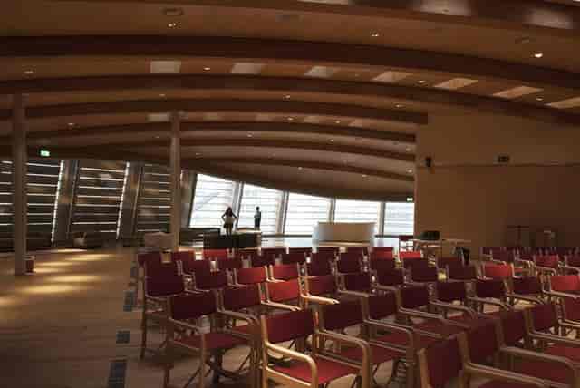 Modern auditorium, tiered seats, wood ceiling, conference, presentation.