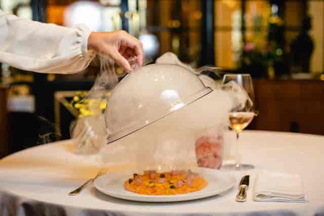Elegant dining at Palazzo Parigi with dramatic smoky food presentation for upscale events.