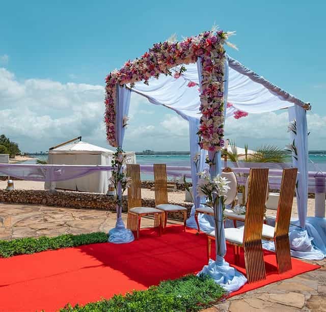 Beachfront wedding ceremony setup with floral chuppah at Coral Beach Hotel, Dar es Salaam.