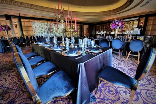 Stirling Club ballroom gala: navy velvet chairs, gold accents, floral decor.