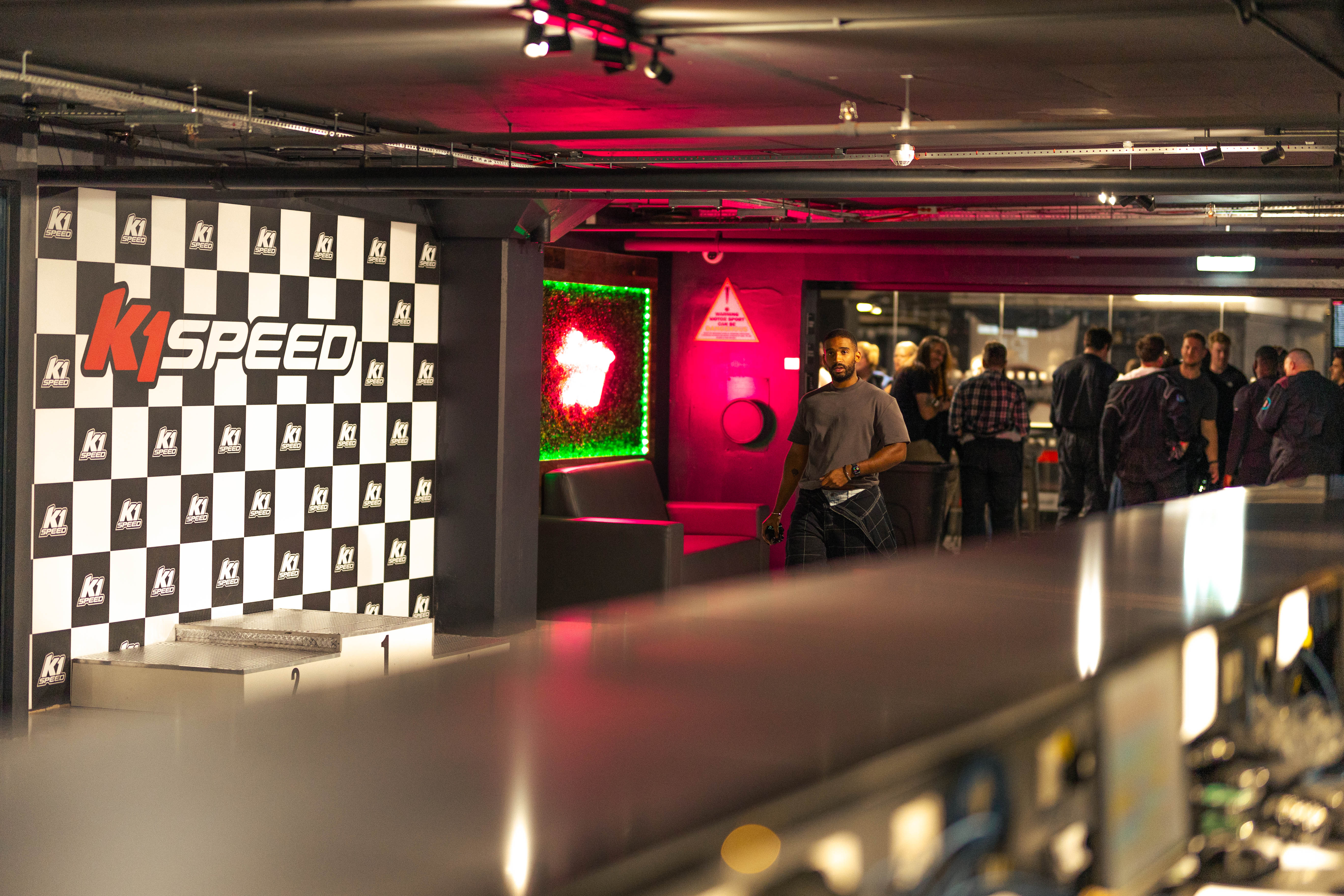 Indoor karting event space at K1 Speed, featuring a checkered backdrop for branding. - Banner
