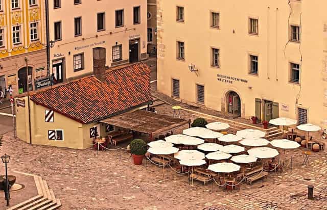 Al fresco reception at Historische Wurstkuchl featuring outdoor umbrella seating for event planners.