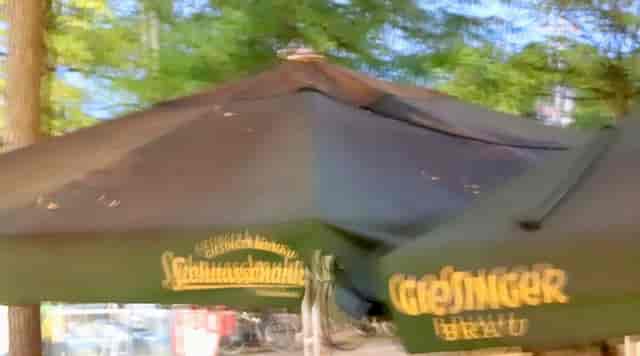 Faded branded umbrella at Giesinger Bräu patio, outdoor event venue, corporate catering setup.