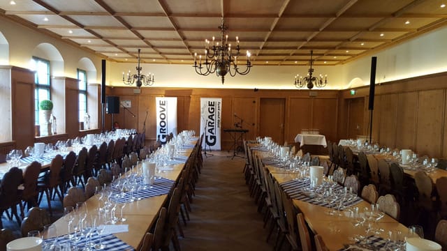 Isar Saal banquet hall with wood paneling for corporate dinners and communal event dining.