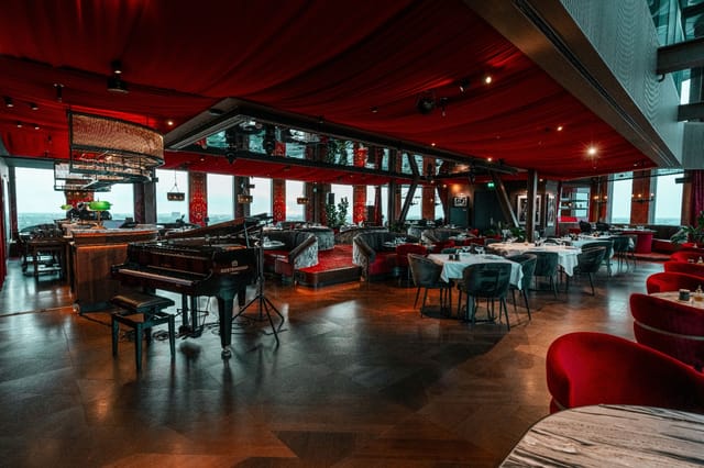 Private dining at Ventuno Sky Lounge featuring red drapery and grand piano for VIP corporate events.