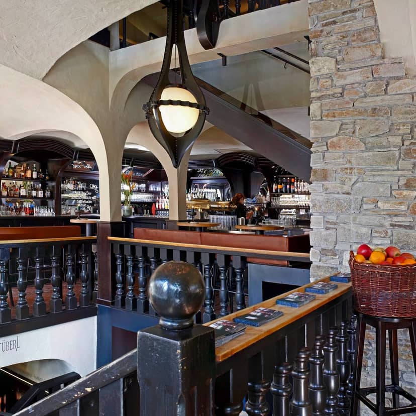 Upscale networking reception at Wirtshaus zur Brezn with warm tiered seating and bar.