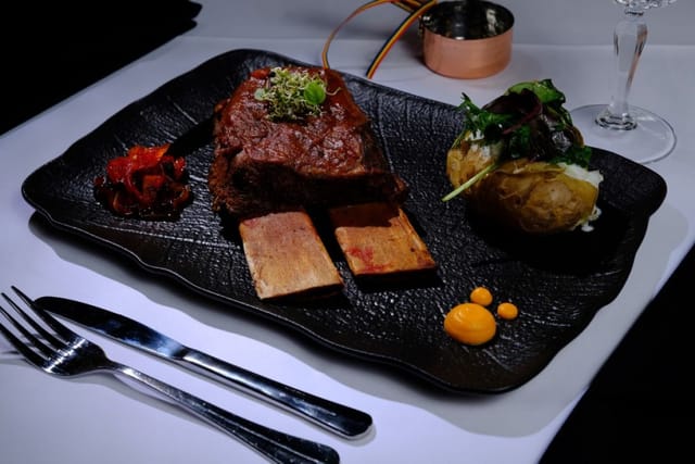 High-end plated entrée on black slate for premium gala dinners and VIP board meetings.