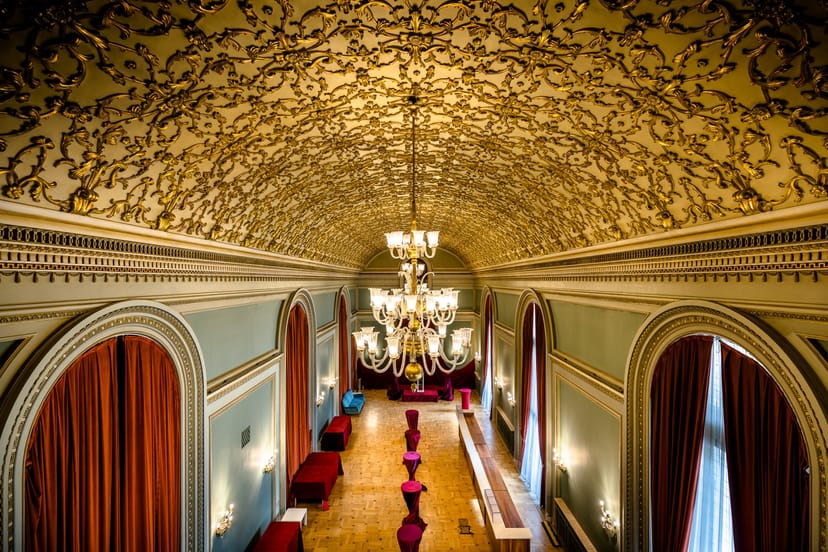 Cocktail reception in Opera Națională București featuring ornate vaulted ceiling and chandelier.