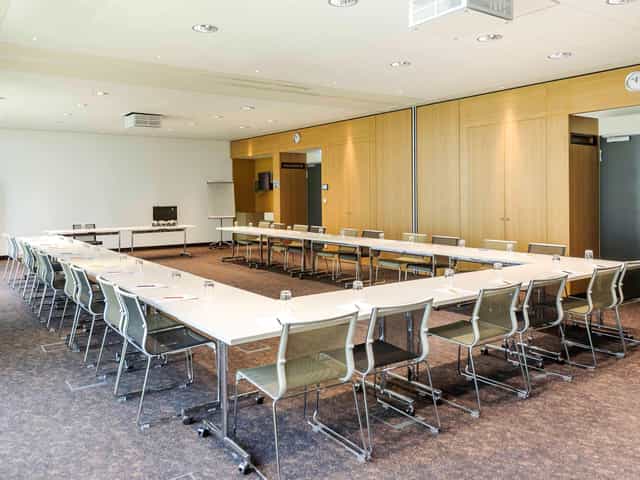 Modern meeting room with U-shaped table, ideal for workshops and strategic planning.