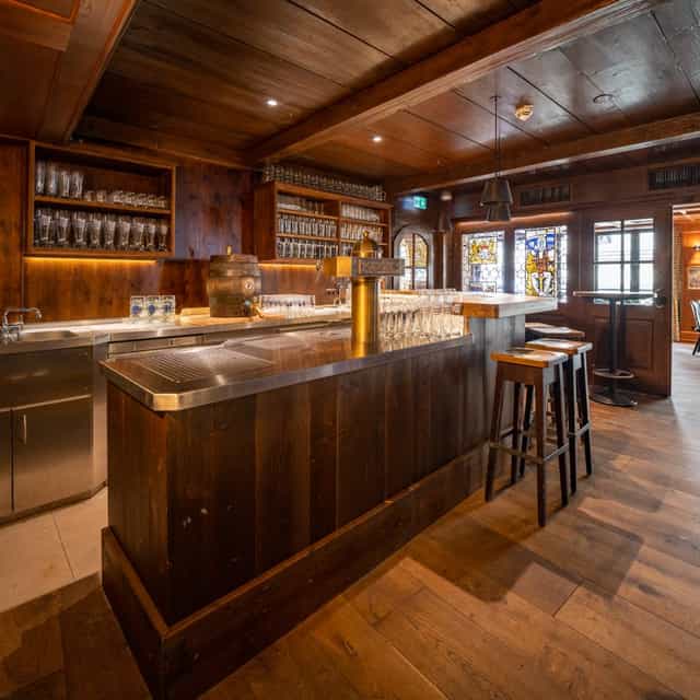 Cozy Bierkutscher-Stube bar with rustic wood finishes for networking events and gatherings.