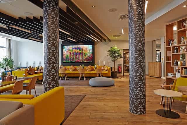 Modern lounge bar in Novotel München, featuring vibrant yellow seating for networking events.