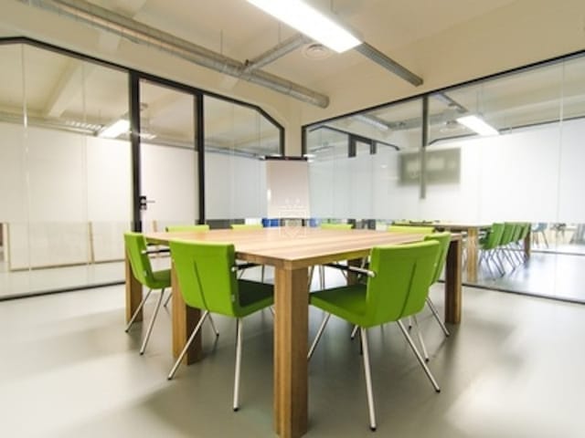Modern glass meeting room with green chairs for creative brainstorming sessions and collaboration.