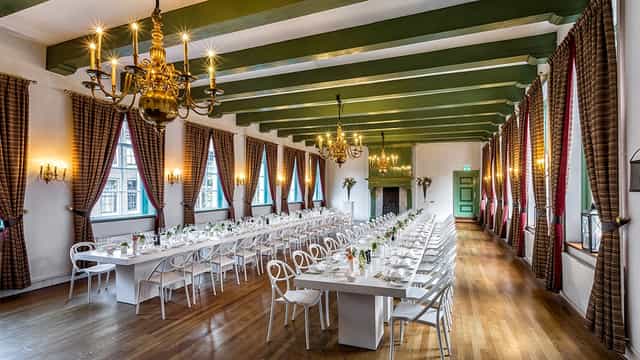 Compagnieszaal long-table banquet setup for historic corporate events and formal dinners.