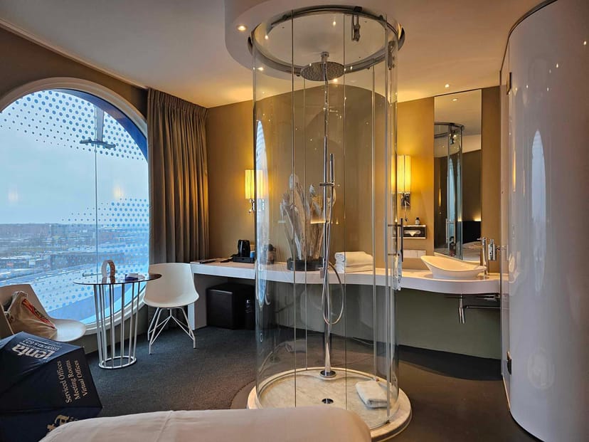 Modern Fletcher Hotel Amsterdam room featuring open-concept shower for corporate business travel.