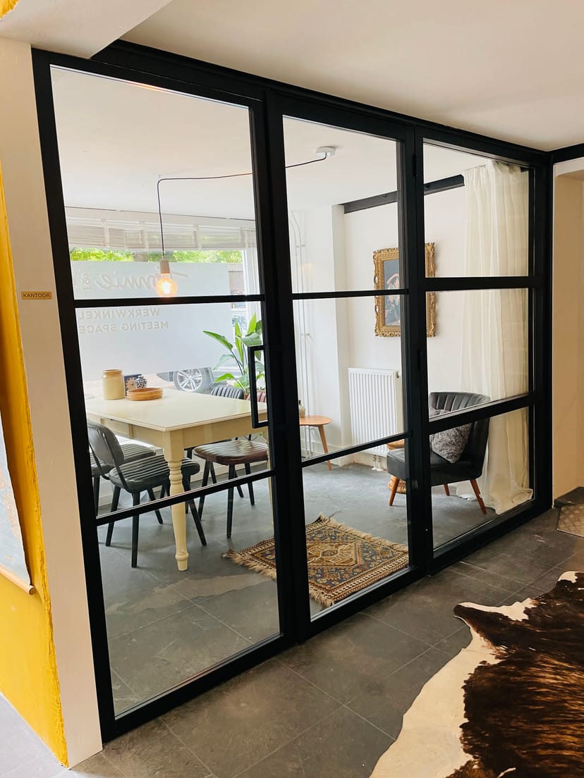 Boutique glass-partition meeting room for small-group strategy sessions and client consultations.