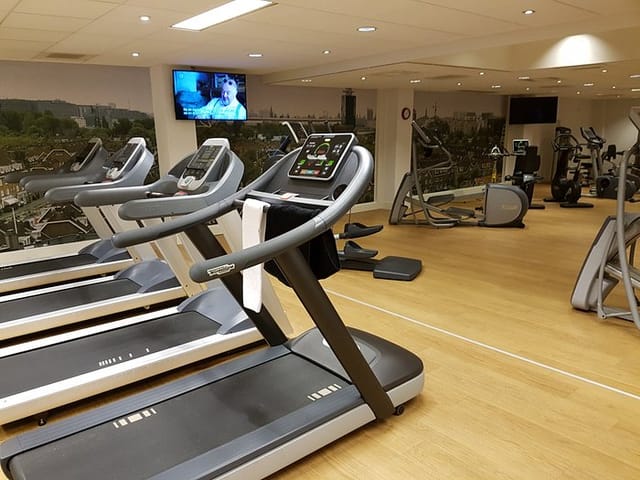 NH Amsterdam Zuid hotel fitness center with modern equipment for wellness and group events.
