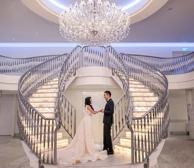Illuminated double staircase at De Koning Trouwzaal for luxury wedding and grand event photography.
