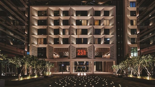 Ernst 25hours Hotel One Central facade with atmospheric lighting for corporate retreats.
