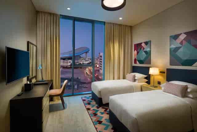 Modern twin guest room at Millennium Al Barsha hotel for business conferences and corporate stays.