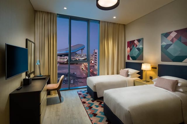 Modern twin guest room at Millennium Al Barsha hotel for business conferences and corporate stays.